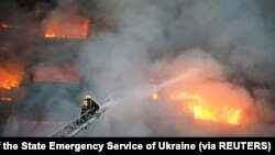 A rescuer puts out a fire in a residential building damaged by shelling, as Russia's attack on Ukraine continues, in Kyiv, Ukraine, March 15, 2022. 