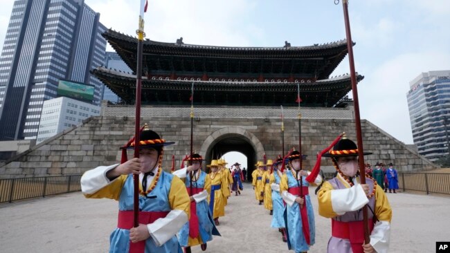 Performers wearing face masks during ceremonies at the Sungnyemun Gate in Seoul, South Korea, March 15, 2022. South Korea had its deadliest day yet of the pandemic recently with a record increase in infections driven by Omicron variant. (AP Photo/Ahn Young-joon)