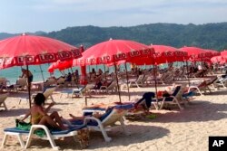 Tourists lounge under umbrellas along Patong Beach in Phuket, Thailand, March 11, 2022.