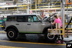 FILE - A female and male assembly line workers works on a Ford Bronco at a Ford plant in Wayne, Michigan, June 14, 2021.