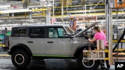 FILE - Assembly line workers build a Ford Bronco at a Ford plant in Wayne, Michigan, June 14, 2021. 