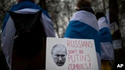 Russians with the Russian anti-war flags wrapped around them, take part in a protest against the Russian invasion of Ukraine in front of the Russian embassy in Vilnius, Lithuania, March 12, 2022.