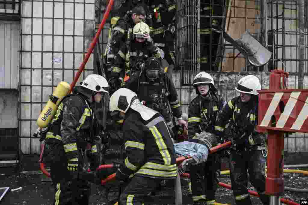 Firefighters remove the body of a woman out of a destroyed apartment building in Kyiv, March 15, 2022, after strikes on residential areas killed at least two people, Ukraine emergency services said.&nbsp;A series of powerful explosions rocked residential districts of Kyiv, just hours before talks between Ukraine and Russia were set to resume.