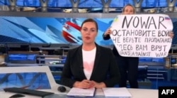 A video grab shows Russian Channel One editor Marina Ovsyannikova holding a poster that reads" Stop the war. Don't believe the propaganda. They are lying to you here" during a live evening news broadcast, in Moscow, March 14, 2022. (Photo by Handout / AFP)