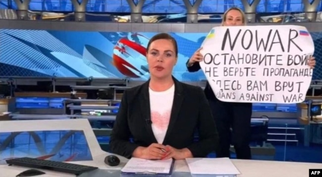 A video grab shows Russian Channel One editor Marina Ovsyannikova holding a poster that reads" Stop the war. Don't believe the propaganda. They are lying to you here" during a live evening news broadcast, in Moscow, March 14, 2022. (Photo by Handout / AFP)
