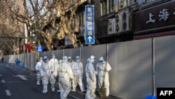 身穿防护服的工作人员在上海一处因发现新冠疫情而被封闭的小区的屏障外。（2022年3月15日）