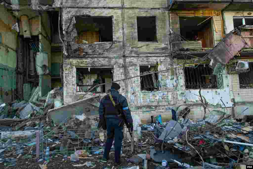 A policeman observes the aftermath of a missile attack against a residential building in Kyiv, Ukraine, March 14, 2022. 