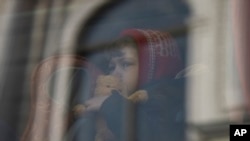 A child who fled the war in Ukraine waits in a bus after arriving to Przemysl train station in Przemysl, Poland, Tuesday, March 15, 2022. (AP Photo/Petros Giannakouris)