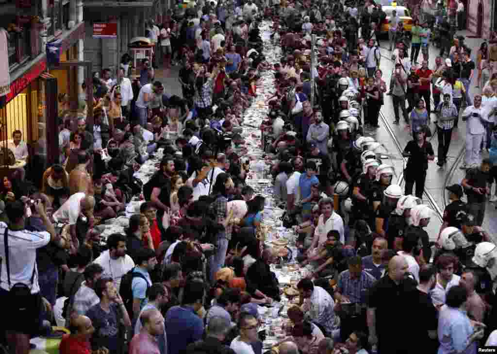 Warga bersiap berbuka puasa pada hari pertama Ramadan sementara polisi berjaga-jaga di dekat Alun-alun Taksim di Istanbul (28/6). (Reuters/Osman Orsal)