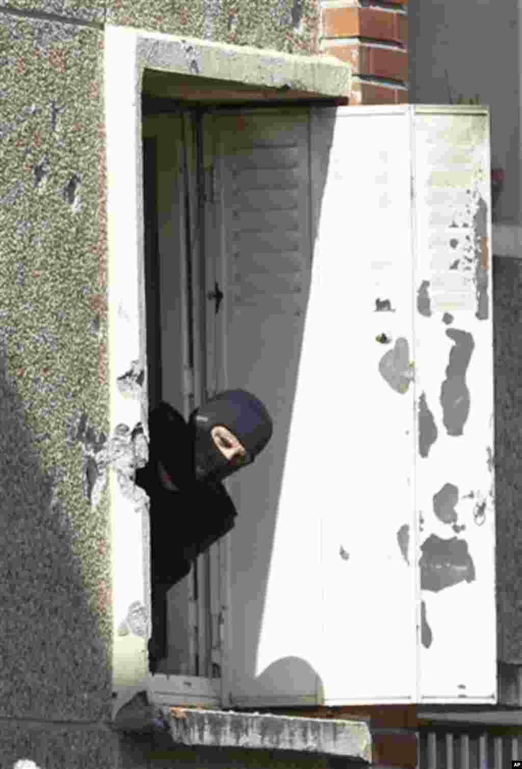 A masked police officer searches for clues at Mohamed Merah's apartment building in Toulouse, France, Friday March 23, 2012. Mohamed Merah, who boasted of killing seven people to strike back at France died on Thursday after being shot in the head by polic