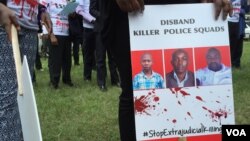 FILE - A protester holds a sign picturing human rights attorney, Willie Kimani; his client, Josephat Mwenda; and their taxi driver, Joseph Muiruri, allegedly killed by police, at a rally in Nairobi, Kenya, July 4, 2016. (J. Craig/VOA)