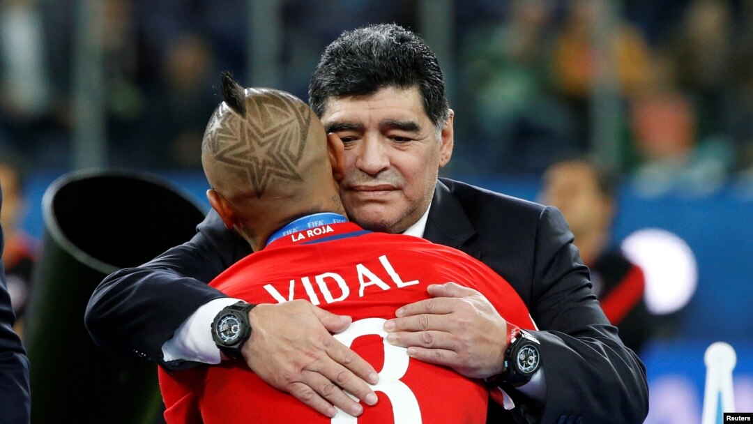 Diego Maradona memeluk pemain Chile, Arturo Vidal, setelah pertandingan Chile melawan Jerman di Stadion St. Petersburg di Rusia, 2 Juli 2017. (Foto:Dok)