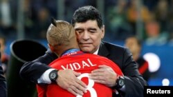 Diego Maradona memeluk pemain Chile, Arturo Vidal, setelah pertandingan Chile melawan Jerman di Stadion St. Petersburg di Rusia, 2 Juli 2017. (Foto:Dok)