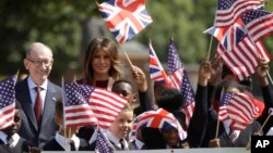 U.S. First Lady Melania Trump and Philip May, the husband of British Prime Minister Theresa May stand with school children during a visit to British military veterans known as "Chelsea Pensioners" at The Royal Hospital Chelsea in central London Friday, July 13, 2018.