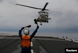 Akiko Ihara, a female flight deck crew of Japanese helicopter carrier Kaga, guides for the landing of a SH-60K Sea Hawk helicopter on the flight deck in the Indian Ocean, Indonesia, Sept. 24, 2018.