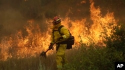 A firefighter with Cal Fire Mendocino Unit walks along a containment line as a wildfire advances, July 30, 2018, in Lakeport, California.