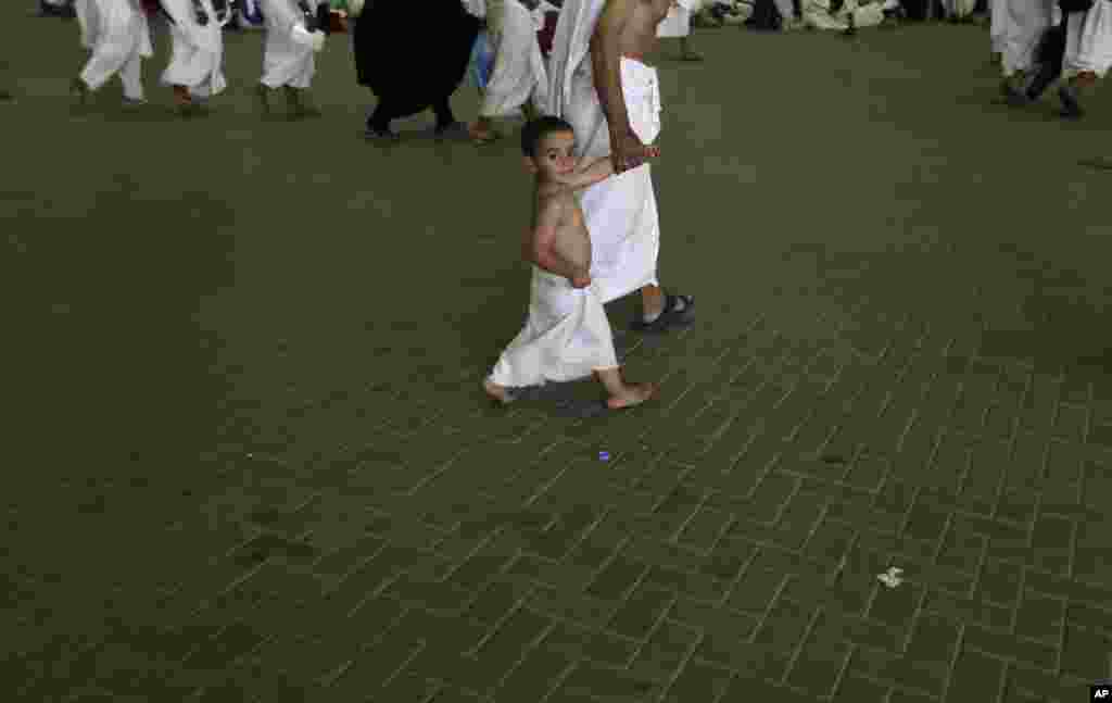 Youssef, 3, a Muslim pilgrim from Egypt walks with his grandfather to casts stones at a pillar near the Saudi holy city of Mecca, Saudi Arabia, October 26, 2012.