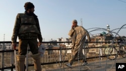 Seorang warga sipil Kashmir berjalan melewati seorang polisi India yang berjaga di dekat pagar berduri saat diberlakukannya jam malam di wilayah Srinagar, India, 9 February 2013. (AP Photo/Mukhtar Khan). Seorang warga Kashmir yang divonis bersalah atas perannya dalam serangan terhadap parlemen India tahun 2001, Afzal Guru, telah dihukum gantung di sebuah penjara India, Sabtu (9/2).