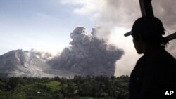 Seorang pria memandangi erupsi Gunung Sinabung dari Tiga Pancur, Sumatera Utara, Rabu (24/6).