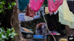 FILE - Mother of two Amsale Hailemariam, a domestic worker who lost work because of the coronavirus, washes her family's clothes outside her small tent in the capital Addis Ababa, Ethiopia, June 26, 2020. 