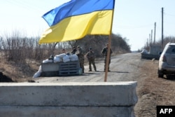 Servicemen of Ukrainian military forces guard a checkpoint, where they hold a position near Kharkiv, March 23, 2022.