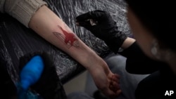 Ukrainian Natalia Tanchynets works on a patriotic-themed tattoo at her workshop in Lviv, Western Ukraine, March 19, 2022.