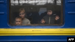 Des enfants regardent par la fenêtre d'un train à Lviv, en Ukraine en guerre contre la Russie, le 3 mars 2022. (Daniel LEAL /AFP)