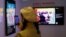 FILE - A visitor takes a photo in front of digital work "Untitled (Self-Portrait)" by Andy Warhol and digital artist Mike Winkelmann, known as Beeple, at the Digital Art Fair, in Hong Kong, China, Sept. 30, 2021.