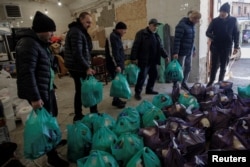 Volunteers carry bags of food from a store to deliver to residents in need, as Russia's attack on Ukraine continues, in Kharkiv, Ukraine, March 28, 2022.