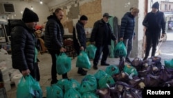 Volunteers carry bags of food from a store to deliver to residents in need, as Russia's attack on Ukraine continues, in Kharkiv, Ukraine, March 28, 2022.