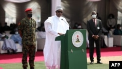 Le président nigérian Muhammadu Buhari (C) prononce un discours lors du lancement des plus grandes pyramides de riz à Abuja, au Nigeria, le 18 janvier 2022. (Photo AFP/ Kola Sulaimon )