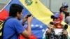 Un hombre toma una foto de una mujer mientras usa una mordaza y una cadena, y sostiene micrófonos durante una manifestación para conmemorar el Día Mundial de la Libertad de Prensa en Caracas, Venezuela, el 3 de mayo de 2016.