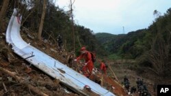 Tim SAR menggunakan anjing pelacak untuk melakukan pencarian kotak hitam di dekat puing-puing di lokasi kecelakaan penerbangan China Eastern di Kabupaten Tengxian di Daerah Otonomi Guangxi Zhuang, China selatan, Selasa, 22 Maret 2022. (Jiang Huaipeng/Xinhua via AP)