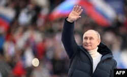 Presiden Rusia Vladimir Putin melambai saat konser menandai ulang tahun kedelapan pencaplokan Krimea oleh Rusia di stadion Luzhniki di Moskow pada 18 Maret 2022. (Foto: AFP/Ramil Sitdikov)