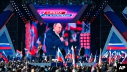 在莫斯科舉辦的一場紀念俄羅斯吞併克里米亞八週年的音樂會上，現場發表演講的俄羅斯總統普京出現在大屏幕上，其背景是一面寫著“為了俄羅斯”的橫幅。（2022年3月18日）