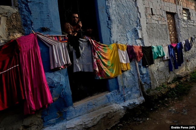 Rosivaldo Ferreira stands in the doorway of her home in the Bom Parto neighborhood of Maceio. She is waiting to be relocated, March 7, 2022. (AP Photo/Eraldo Peres)