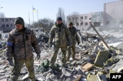 Ukrainian soldiers search for bodies in the debris of a military school hit by Russian rockets the day before, in Mykolaiv, southern Ukraine, March 19, 2022.