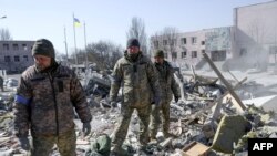 Ukrainian soldiers search for bodies in the debris of a military school hit by Russian rockets the day before, in Mykolaiv, southern Ukraine, March 19, 2022.