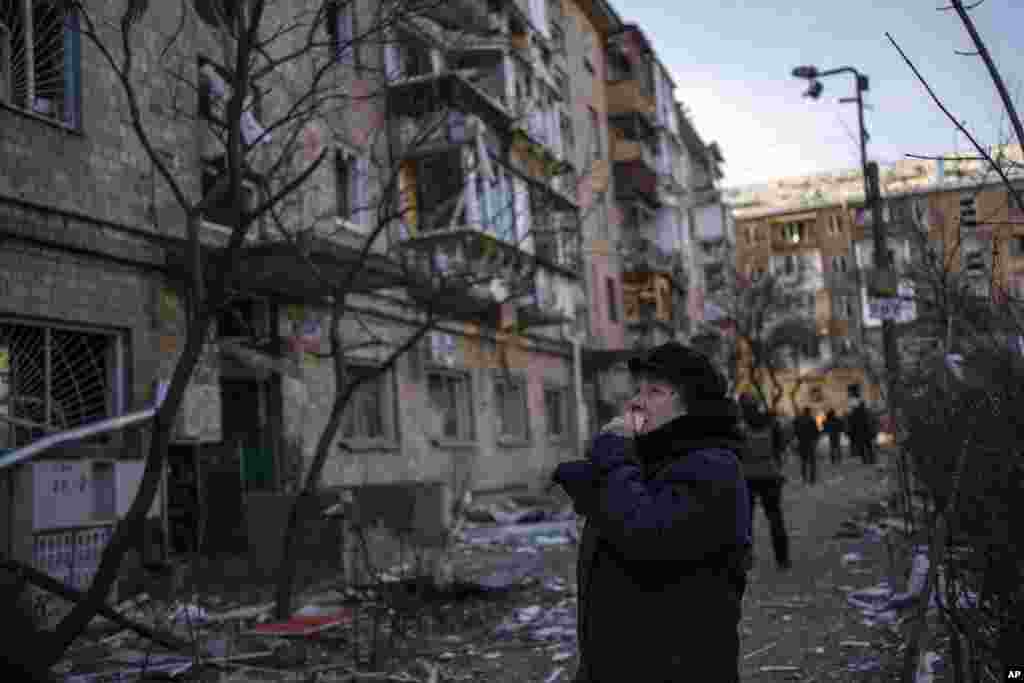 Una mujer mira los edificios residenciales dañados por una bomba en Kiev, Ucrania, el viernes 18 de marzo de 2022. Las fuerzas rusas intensificaron su asalto a las ciudades ucranianas el viernes, con nuevos ataques con misiles y bombardeos en los bordes de la capital, Kiev, y la ciudad occidental de Lviv, mientras los líderes mundiales presionaban para que se investigara los repetidos ataques del Kremlin contra objetivos civiles, incluidas escuelas, hospitales y zonas residenciales.