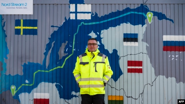 FILE - Axel Vogt, mayor of the German coastal resort town of Lubmin, northeastern Germany, stands in front of an information point container decorated with a map showing the Nord Stream 2 gas pipeline, which was expected to deliver Russian gas to European