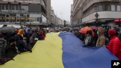 Arhiv - Ljudi nose džinovsku zastavu Ukraine tokom protesta protiv ruske agresije na Ukrajinu, u Beogradu, Srbija, 6. marta 2022. (AP Photo/Marko Drobnjakovic)