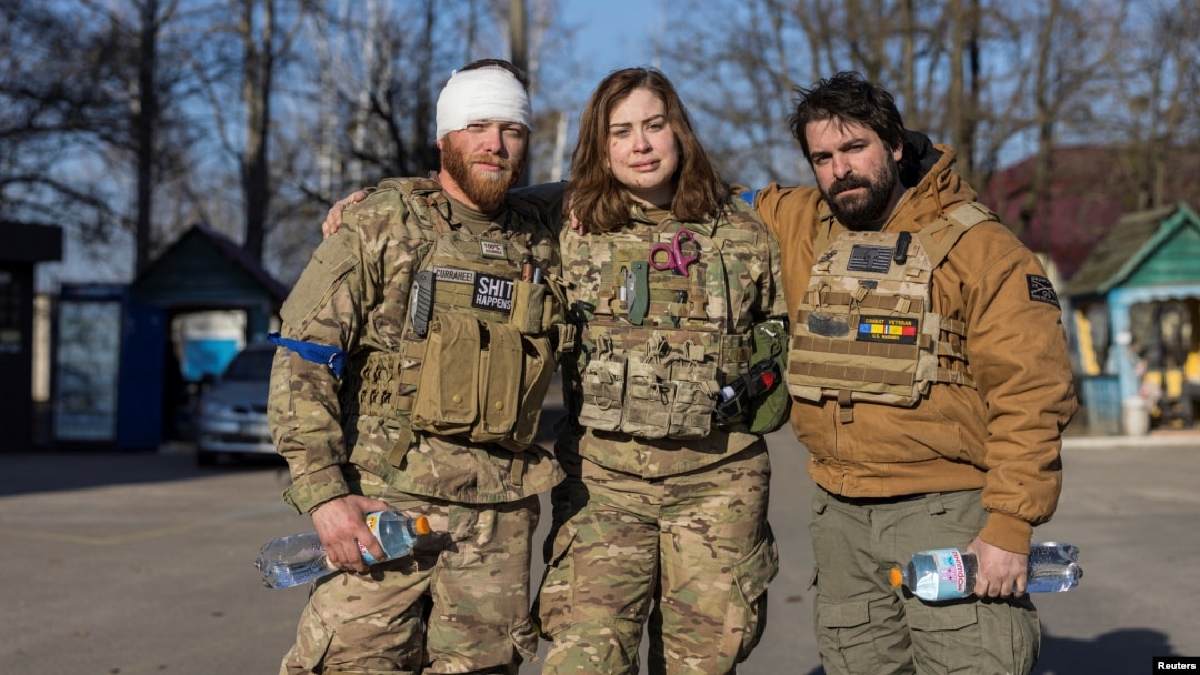 Red Taylor, Alexis Antilla and Rob, members of a group of U.S. volunteer fighters who have taken up arms alongside Ukrainian soldiers, stand in front of a hospital in the town of Brovary, near Kyiv, Ukraine, March 20, 2022.