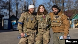 Red Taylor, Alexis Antilla and Rob, members of a group of U.S. volunteer fighters who have taken up arms alongside Ukrainian soldiers, stand in front of a hospital in the town of Brovary, near Kyiv, Ukraine, March 20, 2022.