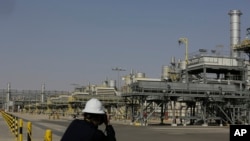 FILE - A photographer takes pictures of the Khurais oil field during a tour for journalists, 150 km east-northeast of Riyadh, Saudi Arabia, June 28, 2021. )