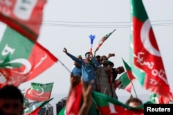 Supporters of Pakistani Prime Minister Imran Khan, chairman of the Pakistan Tehreek-e-Insaf (PTI) political party, wave flags as they attend a public rally in Islamabad, Pakistan, March 27, 2022.