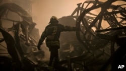A Ukrainian firefighter walks inside a large food products storage facility which was destroyed by an airstrike in the early morning hours on the outskirts of Kyiv, Ukraine, March 13, 2022. 
