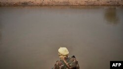 Un soldat malien patrouille sur la rive du fleuve à Konna, le 20 mars 2021.