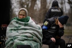 FILE - A Ukrainian police officer is overwhelmed by emotion after comforting people evacuated from Irpin on the outskirts of Kyiv, Ukraine, March 26, 2022.