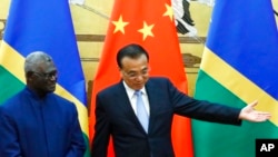 FILE - Solomon Islands Prime Minister Manasseh Sogavare, left, and Chinese Premier Li Keqiang attend a signing ceremony at the Great Hall of the People in Beijing, Oct. 9, 2019.