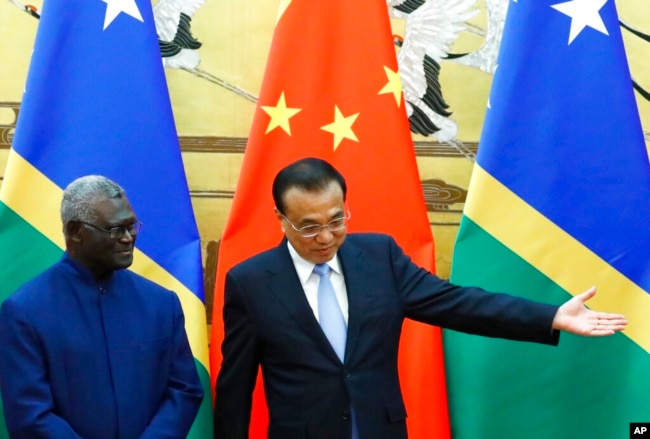FILE - Solomon Islands Prime Minister Manasseh Sogavare, left, and Chinese Premier Li Keqiang attend a signing ceremony at the Great Hall of the People in Beijing, Oct. 9, 2019. (Thomas Peter/Pool Photo via AP, File)